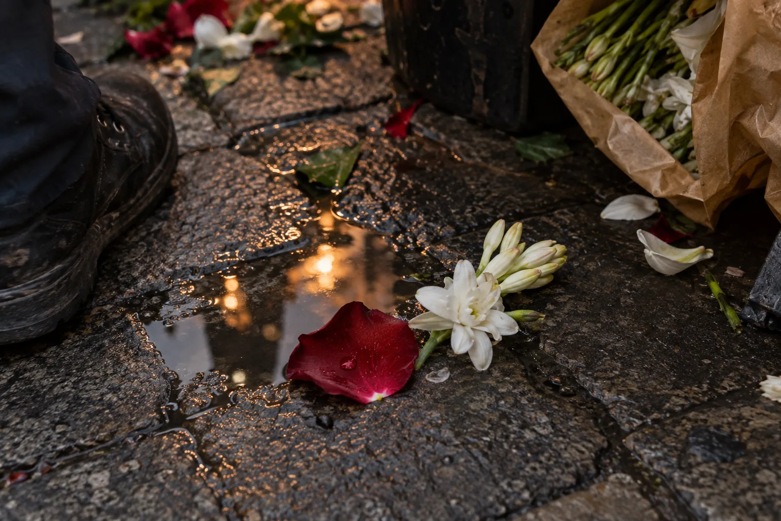 Pétala de rosa vermelha e flor branca sobre o piso molhado de um mercado